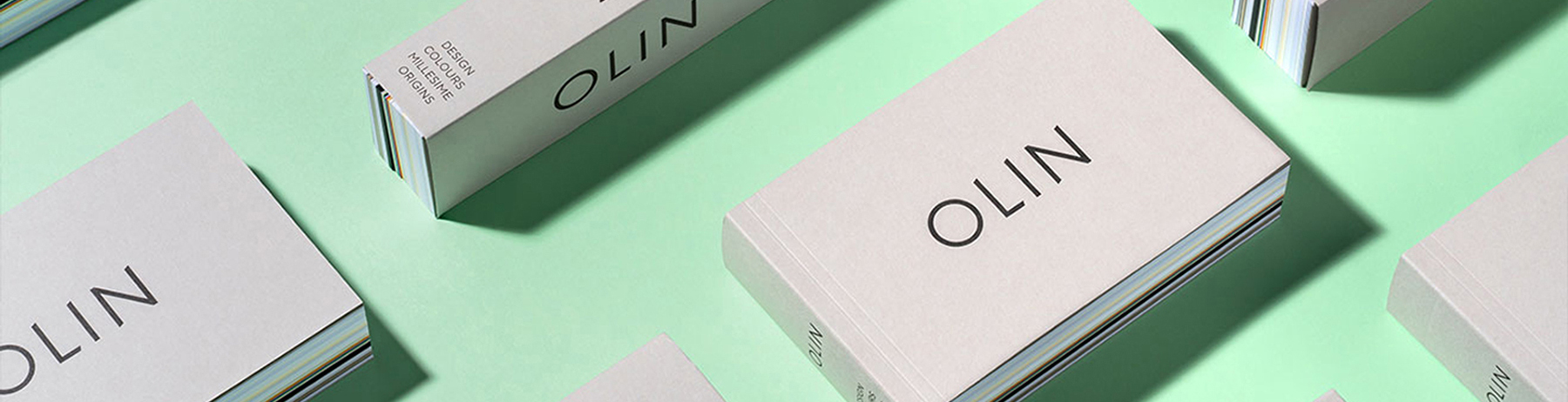 Plusieurs boîtes d’échantillons Olin, disposées sur un fond vert menthe, présentées de manière moderne.